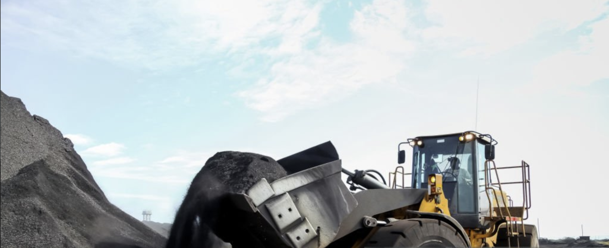 Loader lifting raw material from a stockpile